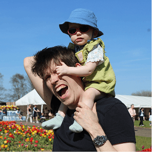 Max with his toddler on his shoulders in a field of tulips
